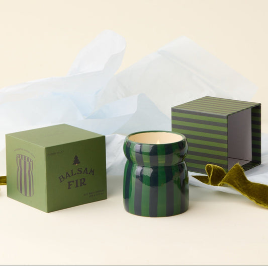 Green striped candle with matching packaging on a light background